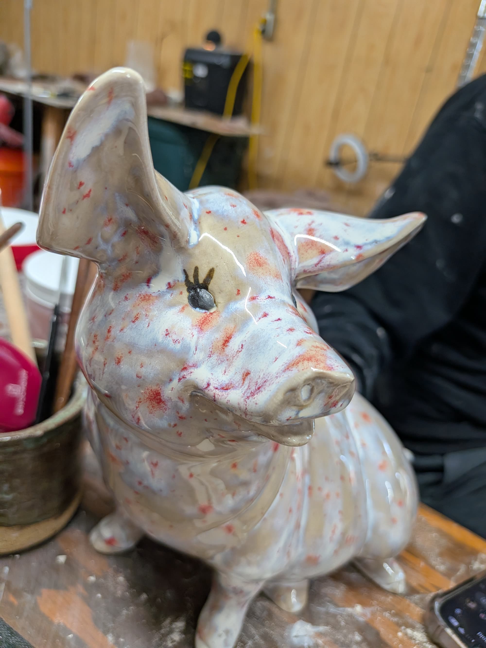 A glossy glazed pig, cream coloured with orange flecks, wide upright ears and a painted eye.